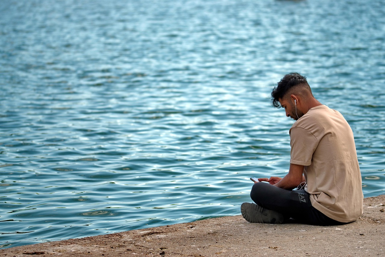 man listening to music by water